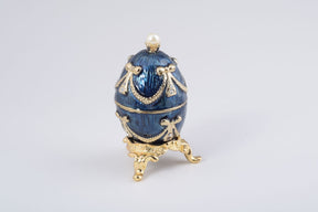 Oeuf Fabergé bleu et or avec une perle sur le dessus